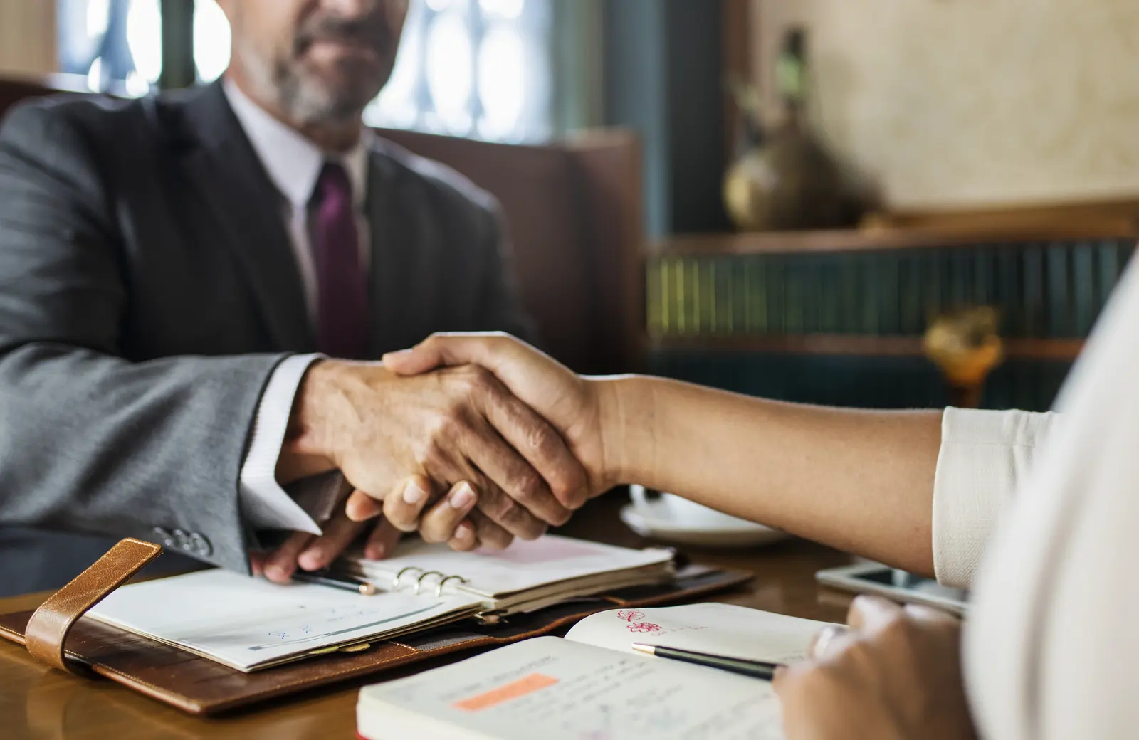 Abogado estrechando la mano de una clienta en una reunión